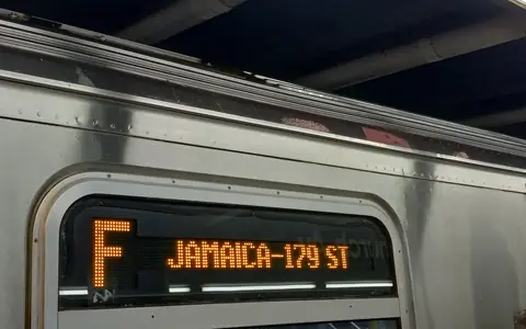 An F train arriving with its destination sign lit