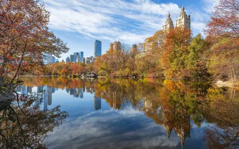 Fall color around The Lake in Central Park with the skyline behind
